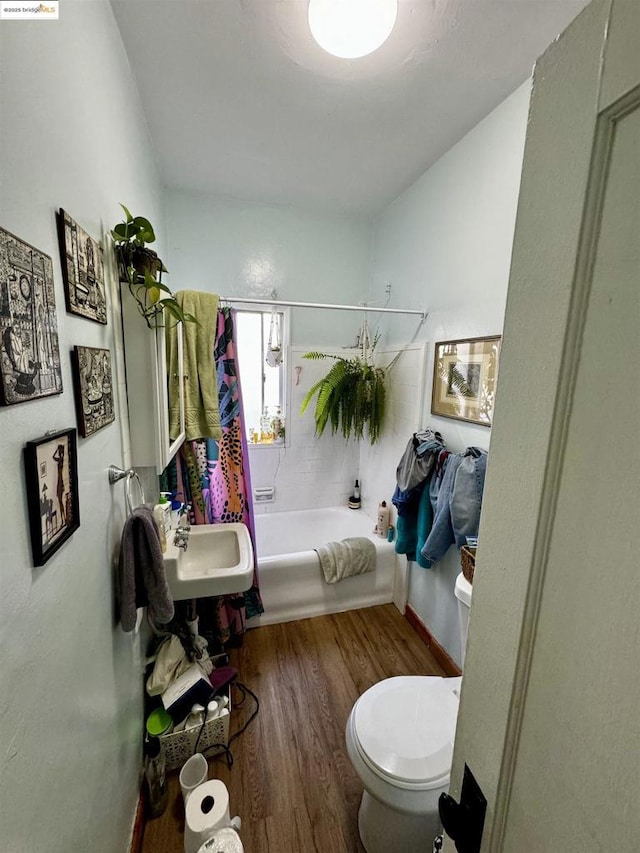 full bathroom with hardwood / wood-style flooring, toilet, sink, and shower / tub combo