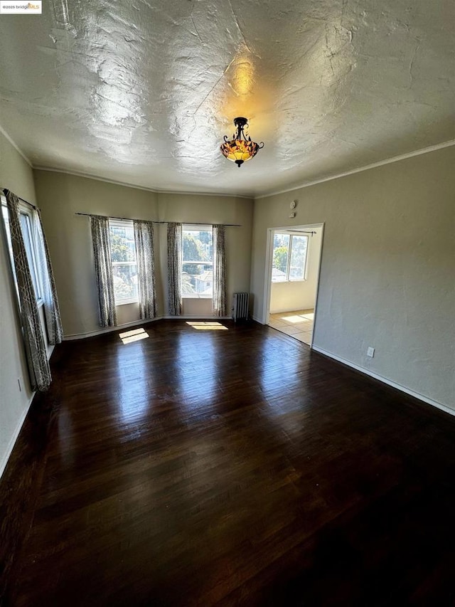 unfurnished living room with dark hardwood / wood-style flooring and radiator heating unit