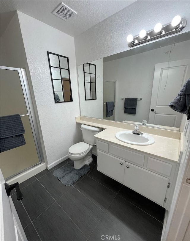 bathroom with vanity, tile patterned flooring, toilet, a textured ceiling, and walk in shower