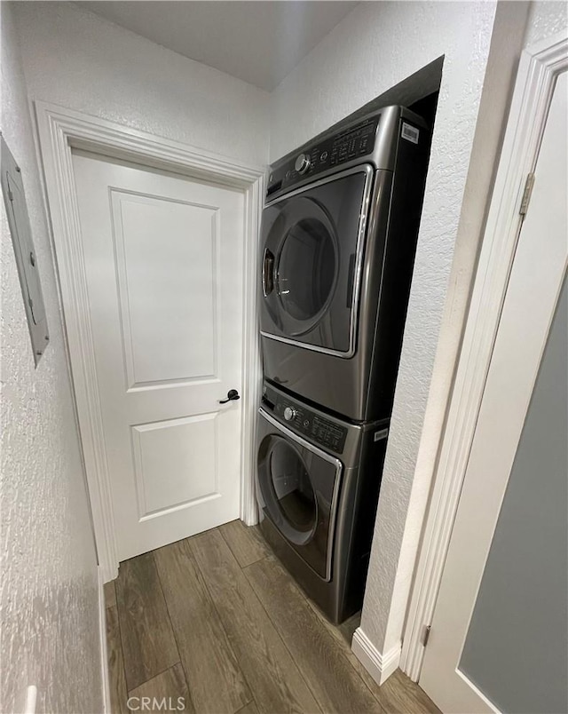 washroom featuring dark hardwood / wood-style flooring and stacked washer and dryer