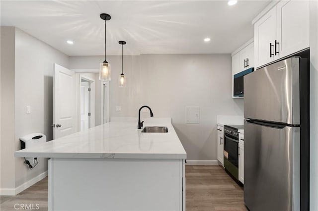 kitchen with stainless steel appliances, a peninsula, a sink, white cabinets, and light wood-type flooring