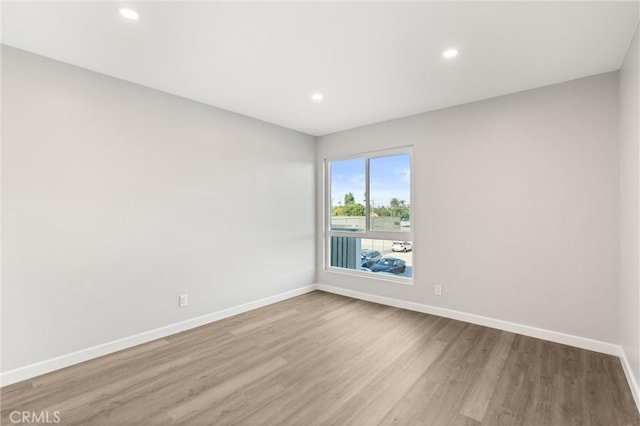 spare room featuring baseboards, wood finished floors, and recessed lighting