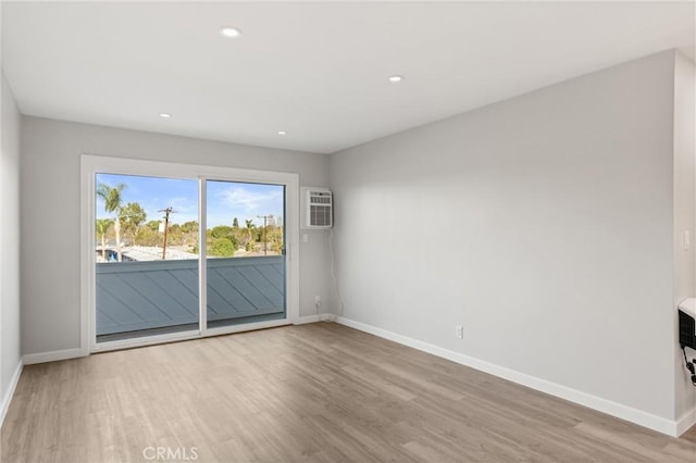 empty room featuring recessed lighting, baseboards, wood finished floors, and a wall mounted air conditioner