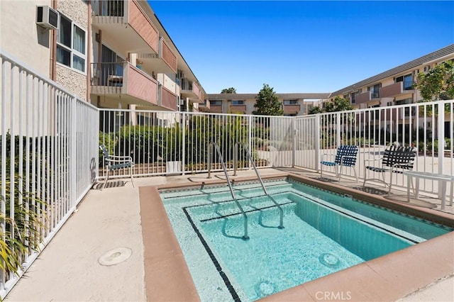 view of pool featuring an AC wall unit and fence