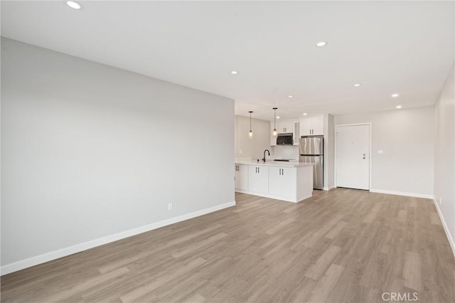 unfurnished living room with light wood-style floors, baseboards, and recessed lighting