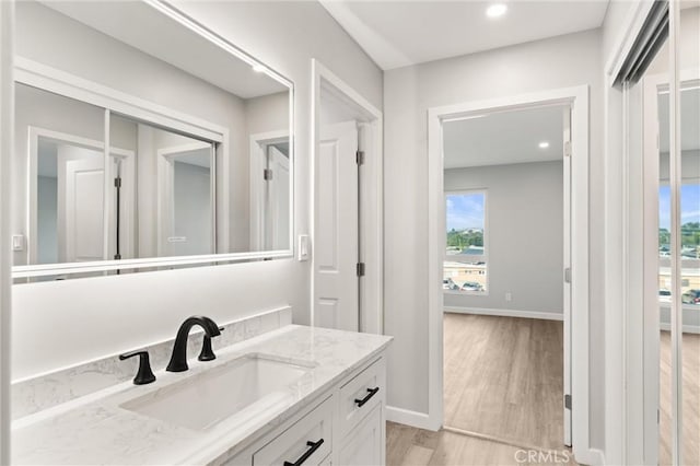 bathroom with recessed lighting, wood finished floors, vanity, and baseboards