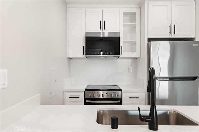 kitchen with stainless steel appliances, light countertops, glass insert cabinets, and white cabinets