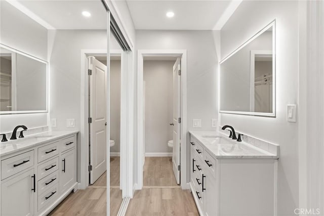 bathroom featuring two vanities, a sink, toilet, and recessed lighting