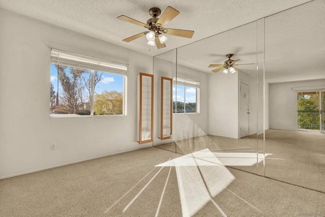 spare room featuring a textured ceiling, ceiling fan, and carpet