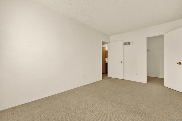 unfurnished room with a textured ceiling and carpet flooring