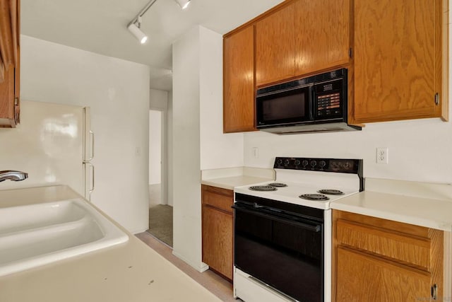 kitchen with electric range, white refrigerator, track lighting, and sink