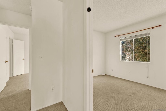 empty room with a textured ceiling and light carpet