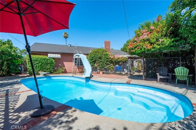 view of pool featuring a diving board and a water slide