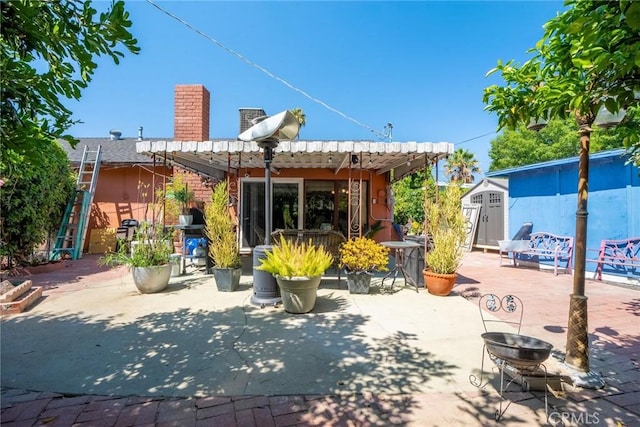 rear view of house featuring a patio area, a pergola, and a shed