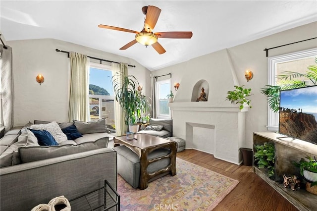 living room featuring ceiling fan, dark hardwood / wood-style flooring, a fireplace, and vaulted ceiling