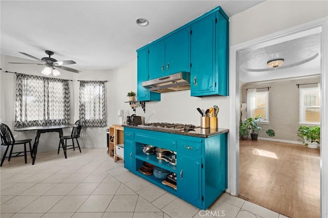 kitchen featuring light tile patterned floors, blue cabinets, ceiling fan, and stainless steel gas cooktop