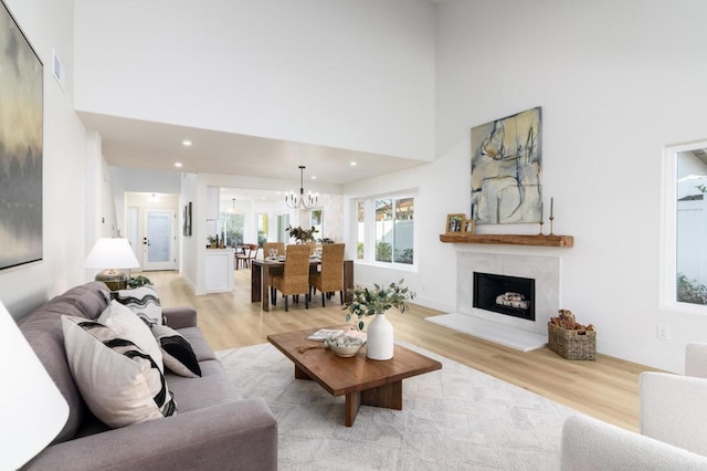 living room with light wood-type flooring, a towering ceiling, and a chandelier