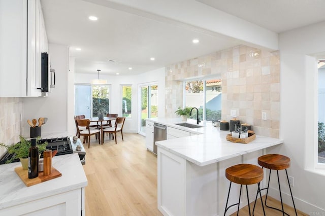 kitchen with a breakfast bar, white cabinets, sink, kitchen peninsula, and stainless steel appliances