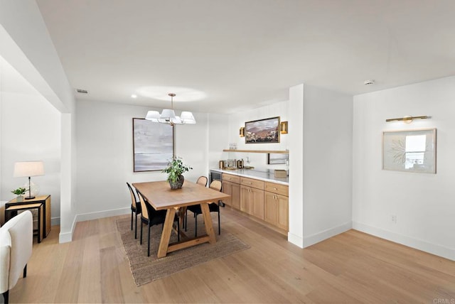 dining space with light hardwood / wood-style floors and a notable chandelier