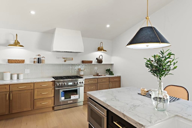 kitchen with tasteful backsplash, light stone counters, ventilation hood, stainless steel appliances, and light hardwood / wood-style floors