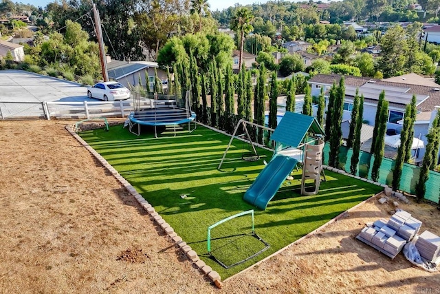 view of community with a playground, a lawn, and a trampoline