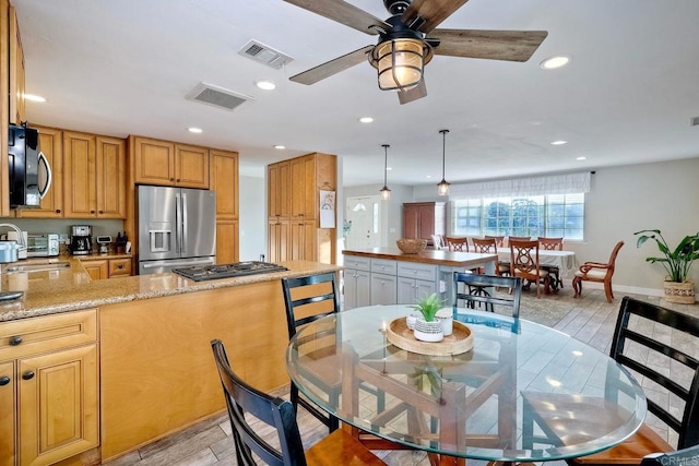 kitchen with kitchen peninsula, light stone countertops, ceiling fan, decorative light fixtures, and stainless steel fridge with ice dispenser