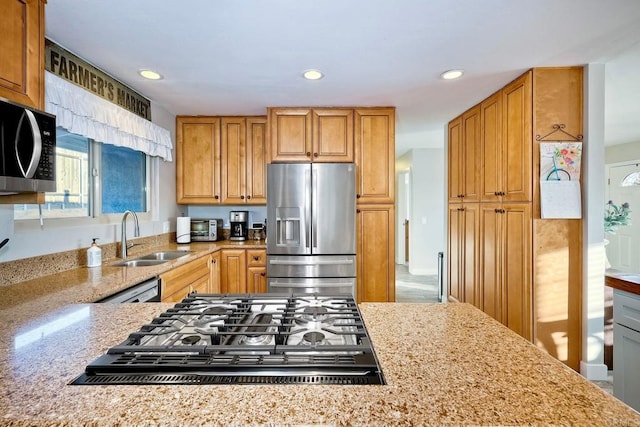 kitchen featuring light stone counters, sink, and appliances with stainless steel finishes