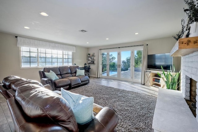 living room featuring a fireplace, hardwood / wood-style floors, a wealth of natural light, and french doors