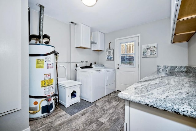 laundry room featuring washing machine and clothes dryer, dark hardwood / wood-style floors, cabinets, and gas water heater