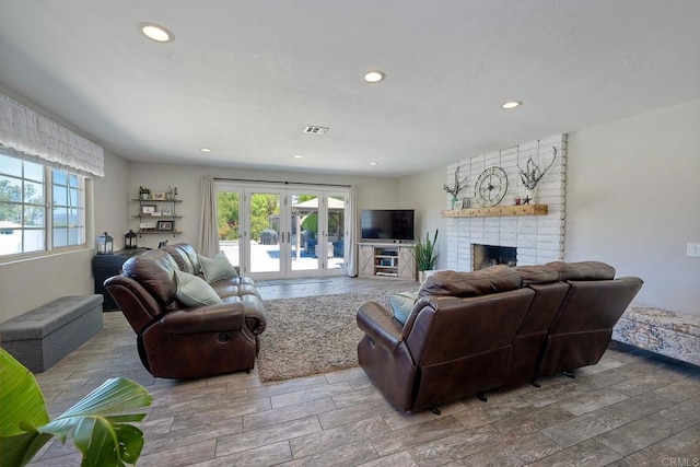 living room with french doors, a brick fireplace, and plenty of natural light