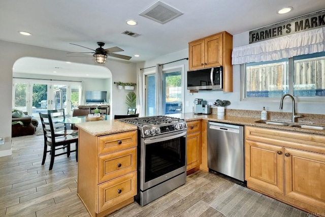 kitchen with kitchen peninsula, appliances with stainless steel finishes, ceiling fan, and sink