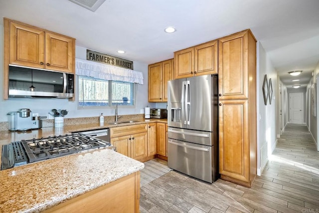 kitchen with appliances with stainless steel finishes, light stone counters, and sink