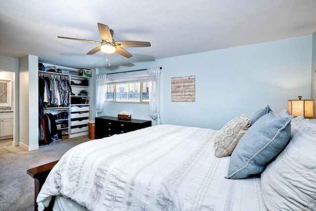 carpeted bedroom featuring a closet, ensuite bath, and ceiling fan