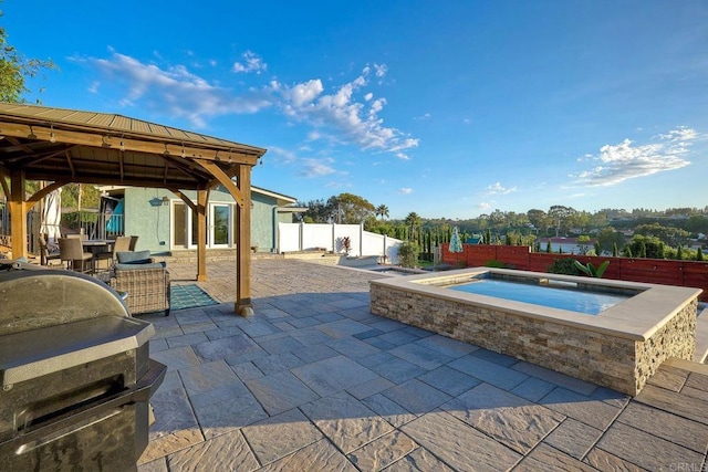 view of patio featuring an in ground hot tub, a gazebo, and grilling area