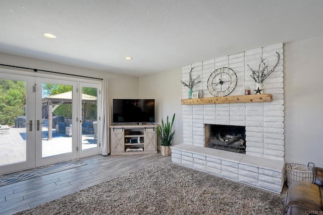 unfurnished living room with a fireplace, french doors, and wood-type flooring