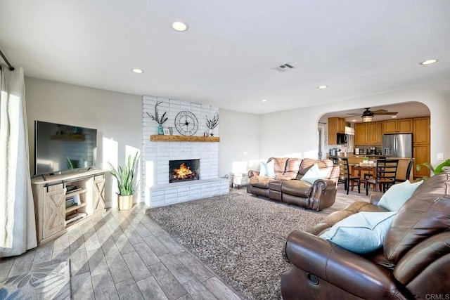 living room featuring a brick fireplace and ceiling fan