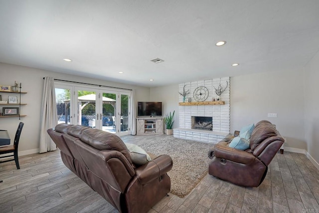 living room with a fireplace, french doors, and light wood-type flooring