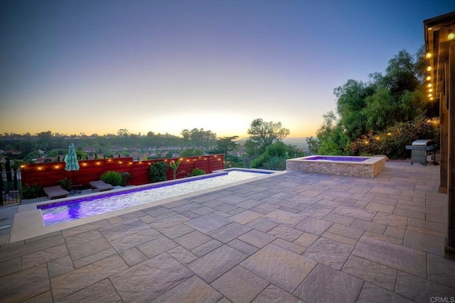 patio terrace at dusk with area for grilling and a pool with hot tub