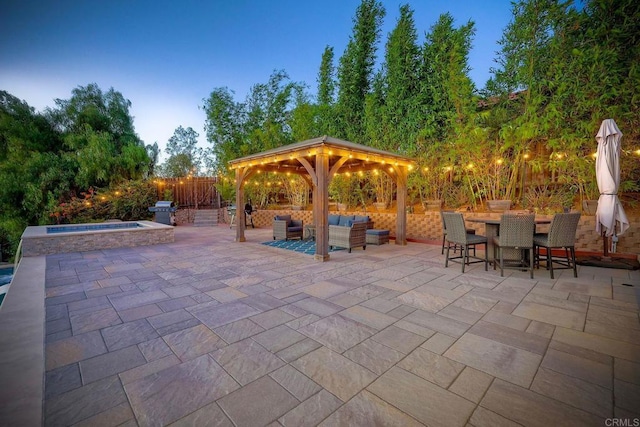 patio terrace at dusk featuring an in ground hot tub, a gazebo, an outdoor living space, and area for grilling