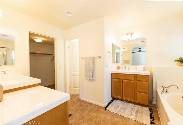 bathroom with a bathing tub, vanity, ceiling fan, and tile patterned floors