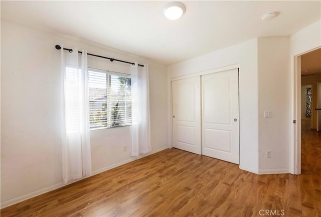 unfurnished bedroom featuring wood-type flooring and a closet