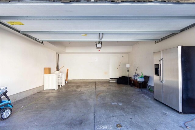 garage featuring stainless steel fridge with ice dispenser and a garage door opener