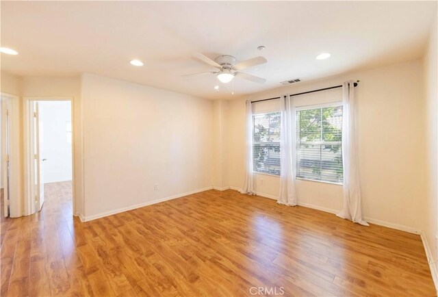 spare room with ceiling fan and light wood-type flooring