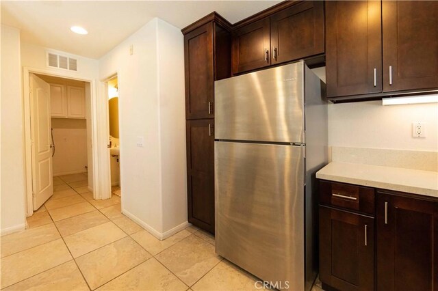 kitchen featuring stainless steel refrigerator, dark brown cabinets, and light tile patterned floors