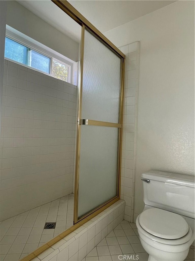 bathroom with toilet, tile patterned floors, and walk in shower