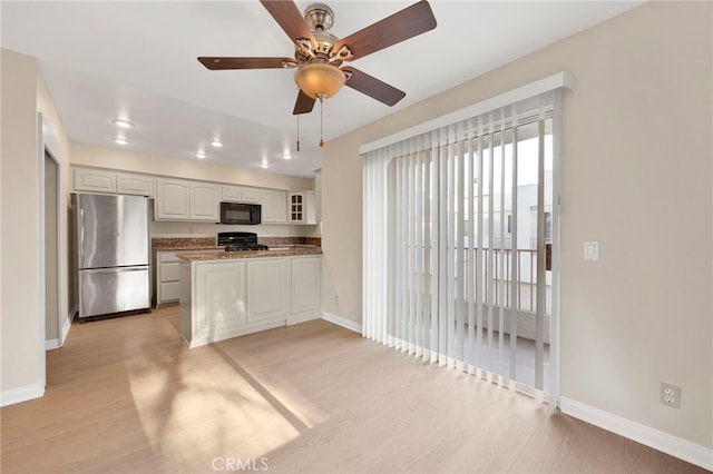 kitchen with range, white cabinets, ceiling fan, stainless steel fridge, and kitchen peninsula