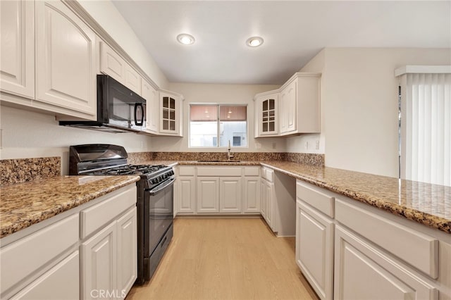 kitchen featuring light stone countertops, sink, black appliances, light hardwood / wood-style flooring, and white cabinetry