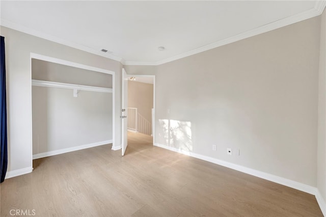 unfurnished bedroom with hardwood / wood-style flooring, crown molding, and a closet