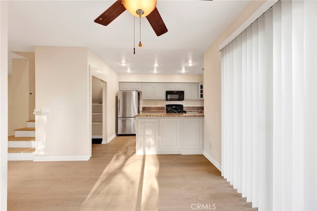 kitchen featuring stove, light wood-type flooring, ceiling fan, stone countertops, and stainless steel refrigerator