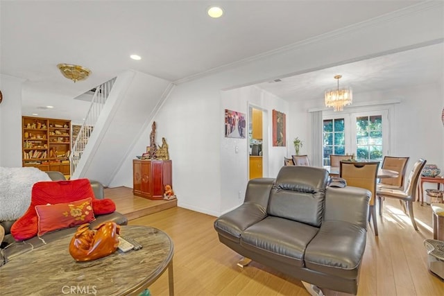 living room featuring crown molding, light hardwood / wood-style flooring, and a notable chandelier